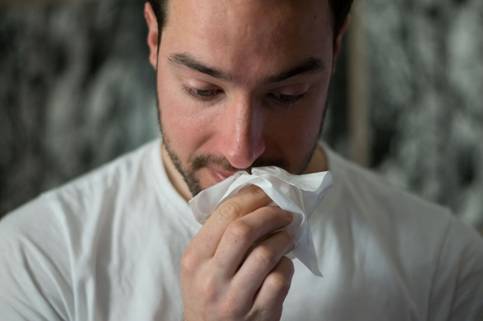 A man down with flu holding tissue.