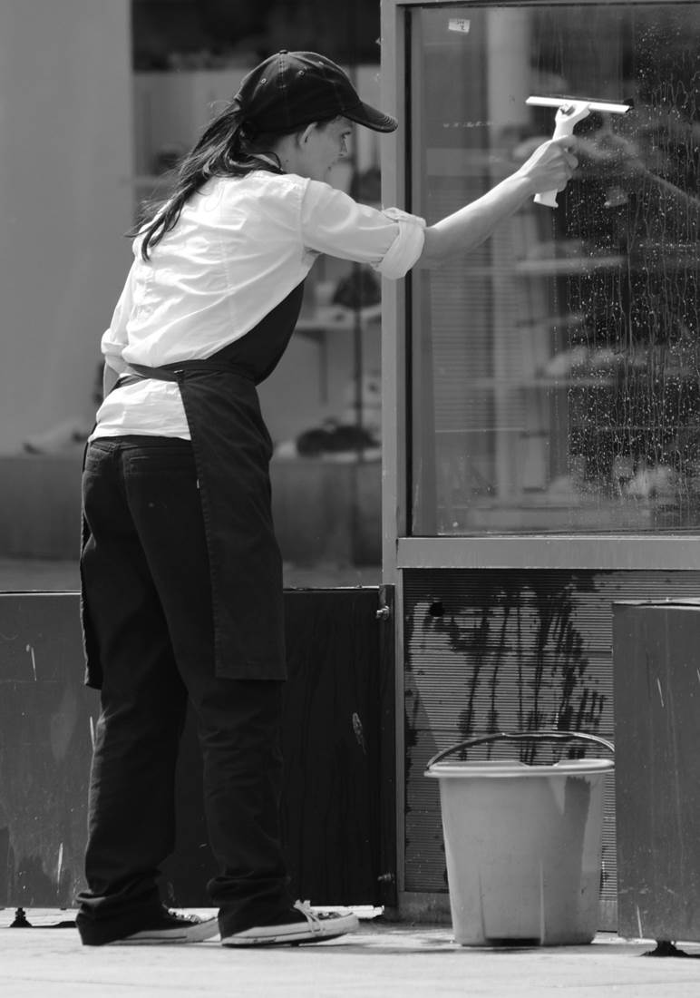 A professional window cleaner washing windows of a store front